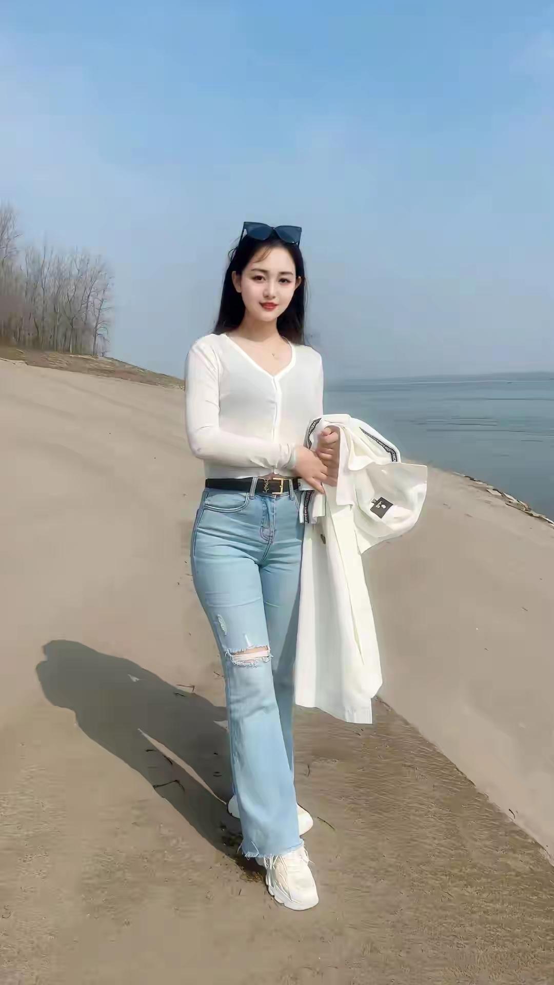 海边漫步，白色外套与牛仔裤的清新搭配，阳光下的美好时光。