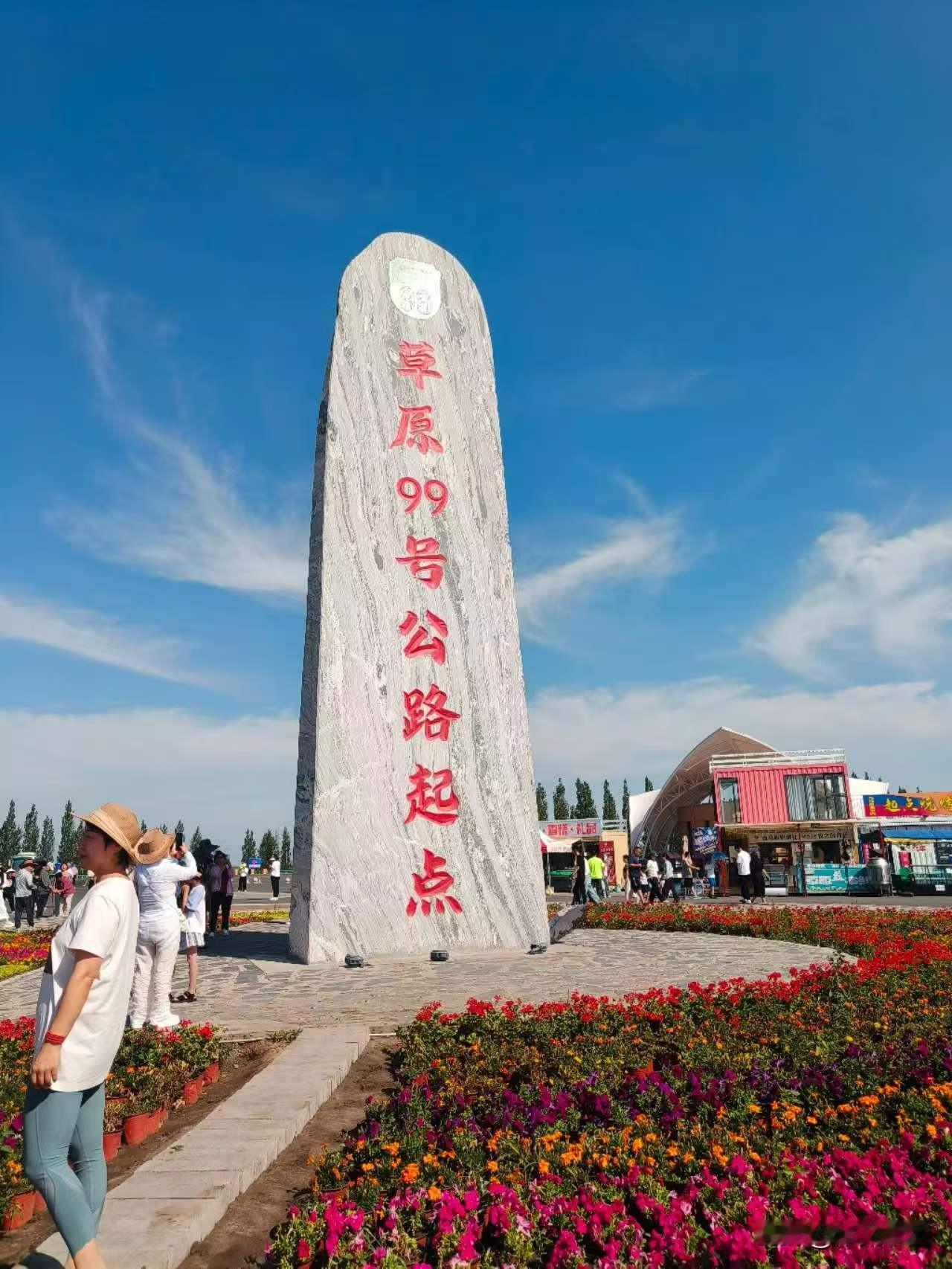 草原99号公路起点。
碑下人头攒动，自拍杆如林。停车场里引擎轰鸣混着喇叭尖叫，休