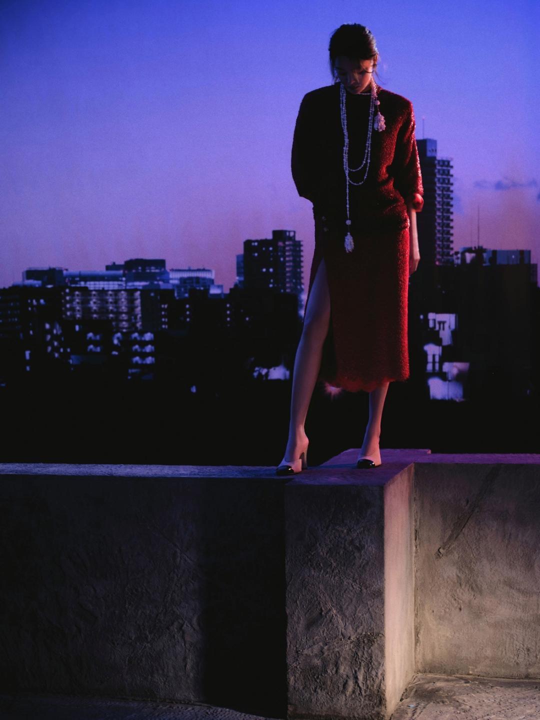 暮色熔成紫调穹顶，红焰织就衣袂锋芒，辛芷蕾伫立在城市天台的暮色里，用一身红金交织