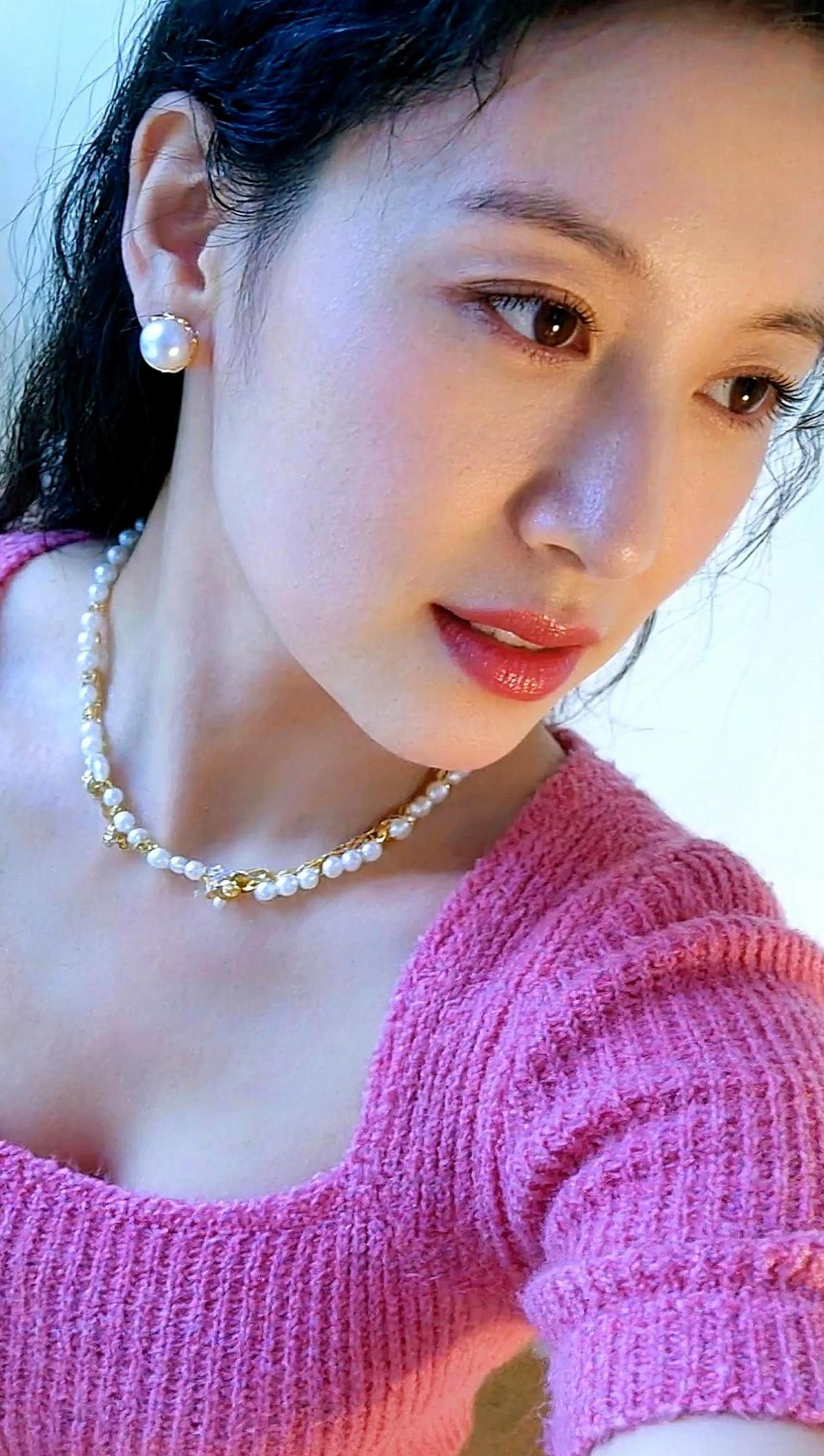 在温柔的粉衣映衬下，她仿佛是生活中的一抹暖阳，不经意间点亮了平凡的日子。细腻的针