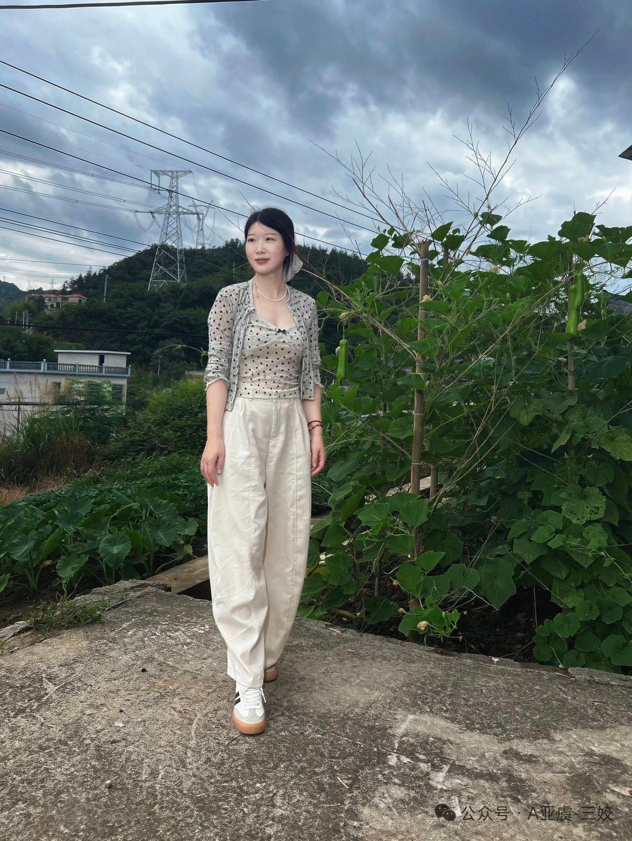 她站在田间，穿着休闲装。