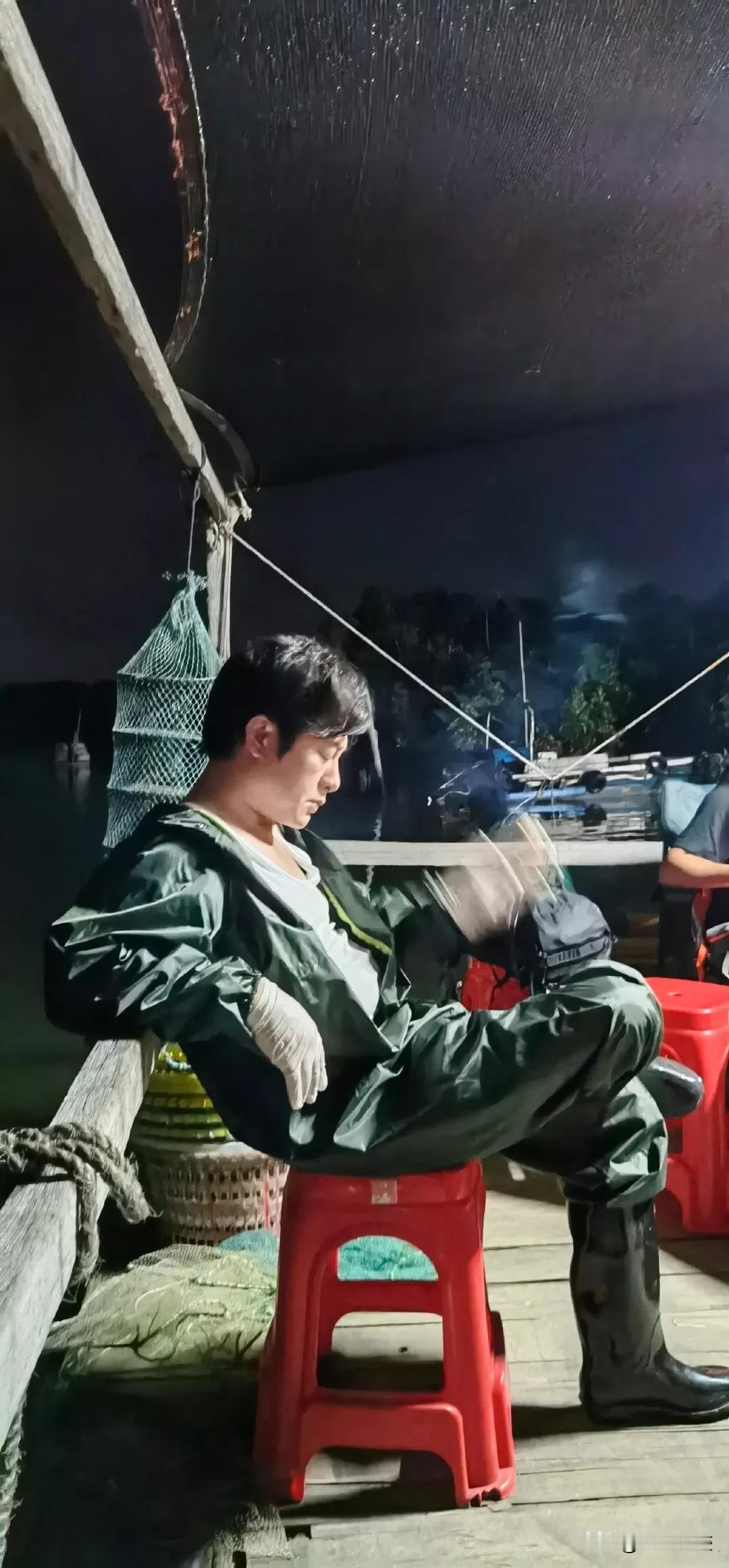这照片有什么好看的？环境又脏又乱，光线又暗，翘着腿，穿着双雨鞋和邹巴巴的连体雨衣