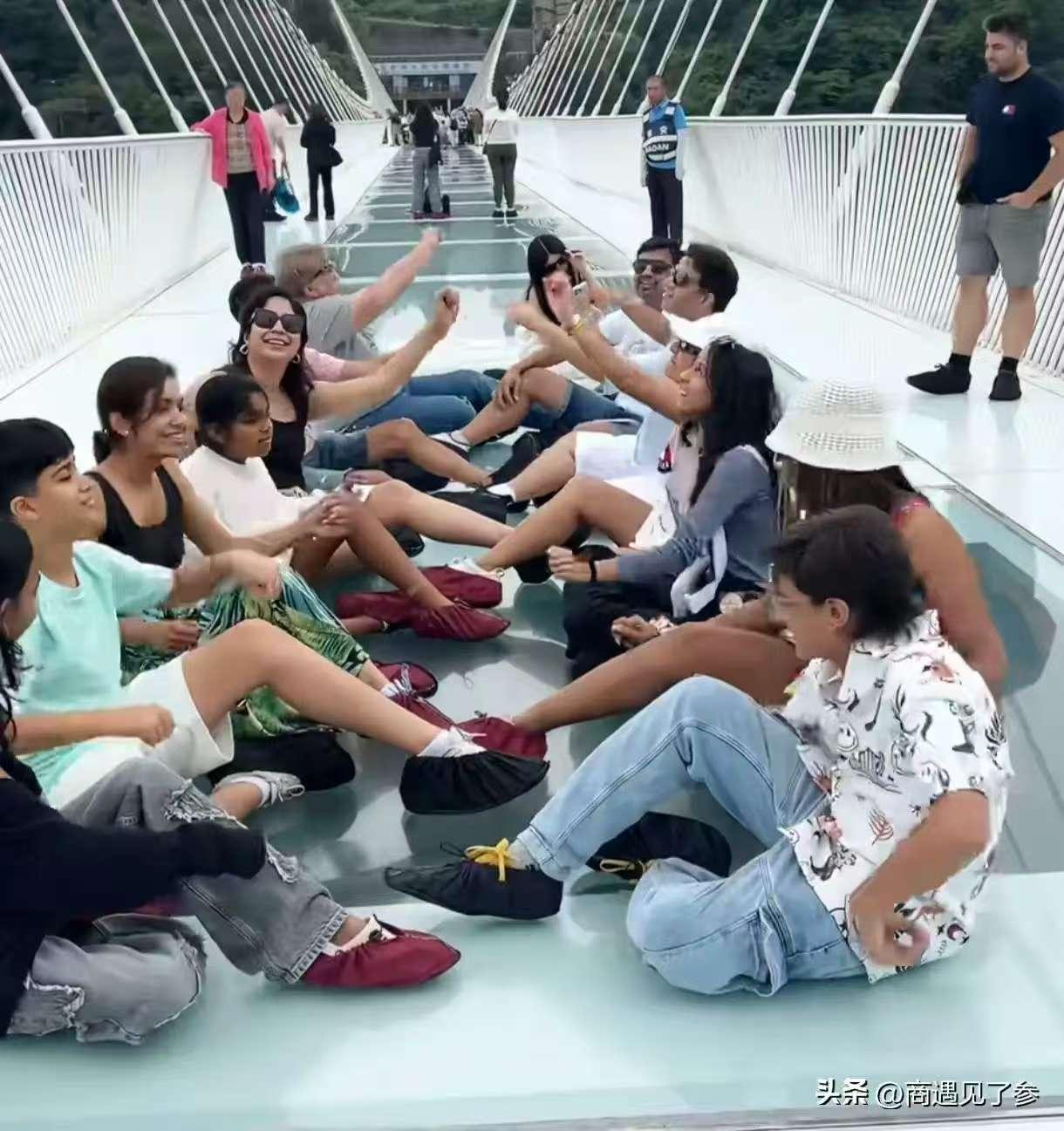 一群印度人，
在张家界玻璃栈道上，坐了一片，
堵的其他游客没法通行，工作人员提醒
