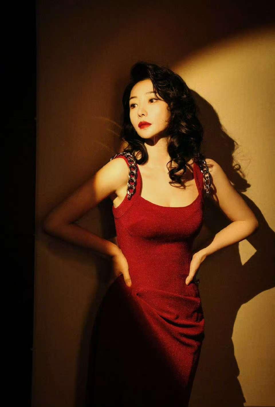 手捧白玫瑰的柳岩，直接把港风美人的氛围感拉满到极致！一袭酒红色闪钻吊带裙贴身剪裁