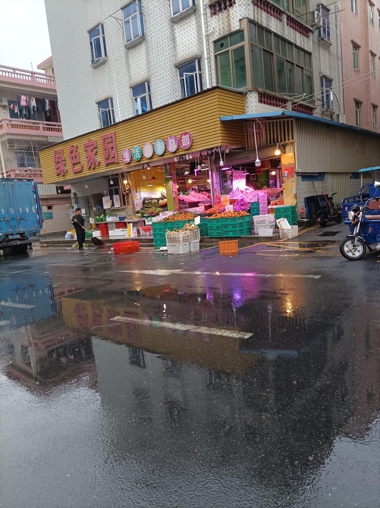 随手拍张照下雨天路上的风景，水果店一早就开门了，上班的人冒雨前行，值巡保安坚守岗