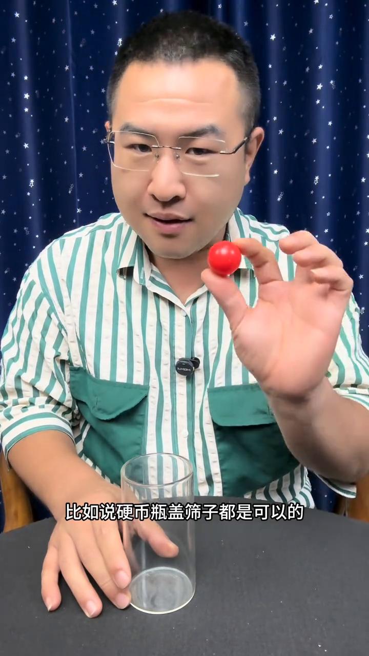 大家好，把一颗小红球放到杯子里边，没有任何的问题。接下来把小球倒在手上，从这个位