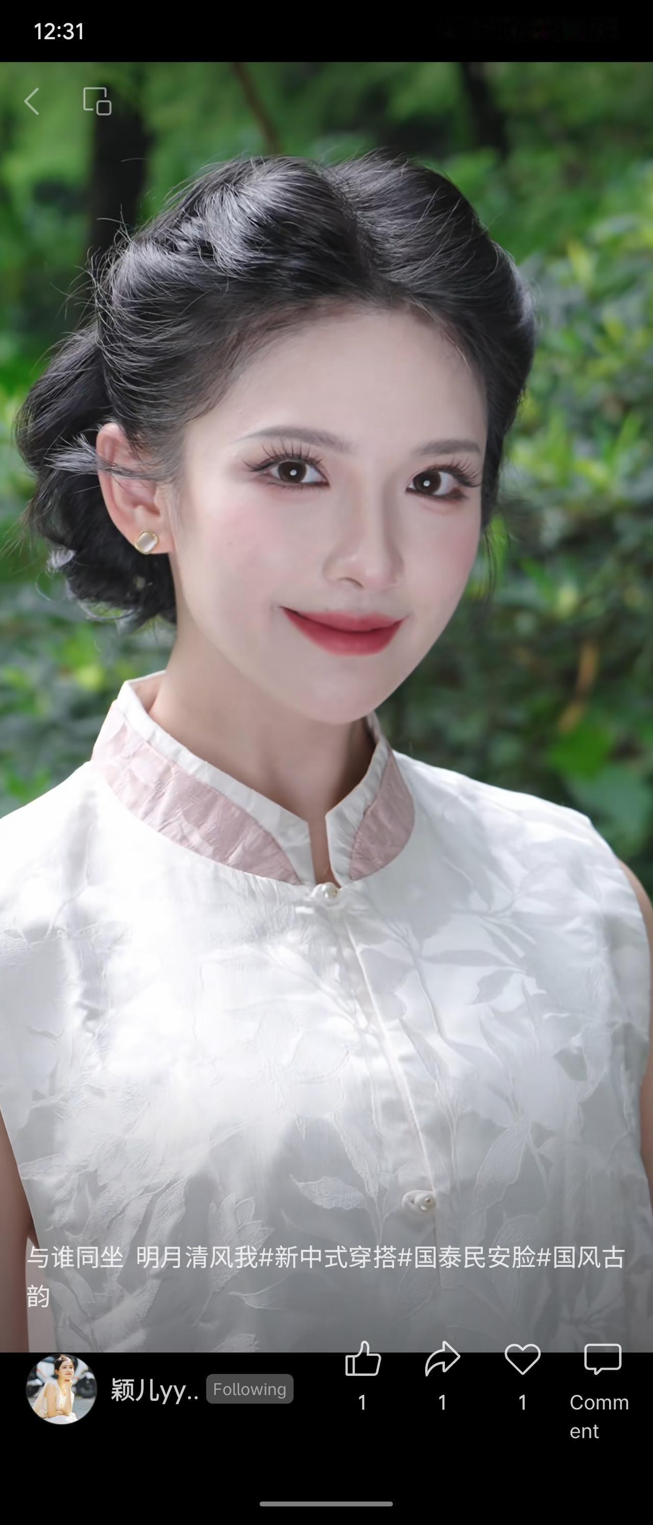 葱郁绿意环绕身旁，温婉盘发勾勒出柔和线条。一身白调暗纹新中式上衣缀着柔粉领边，眉