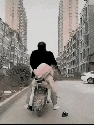 女孩上学时，一只鞋子掉在了地上，她赶紧下车去捡鞋子。

这时，爸爸坐在电动车上，