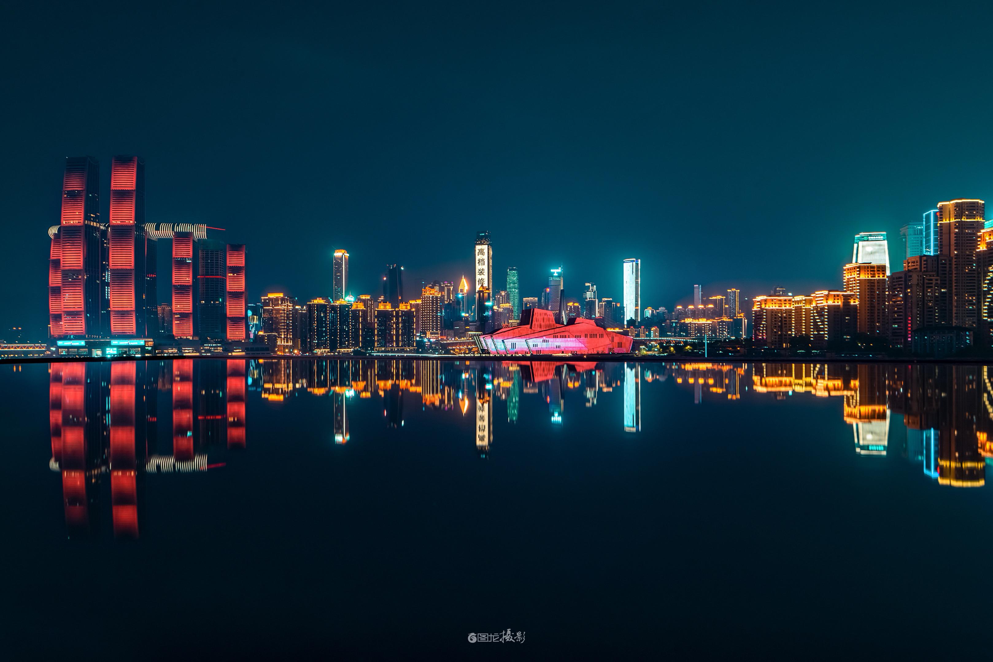 重庆的夜。嘉陵江把城市的光揉成软的镜，红塔的暖撞着蓝楼的凉，那座粉檐的...