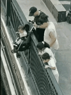 一家六口来到海边看风景，坐在婴儿车上的小男孩看见大海后非常的开心。于是，父母把婴