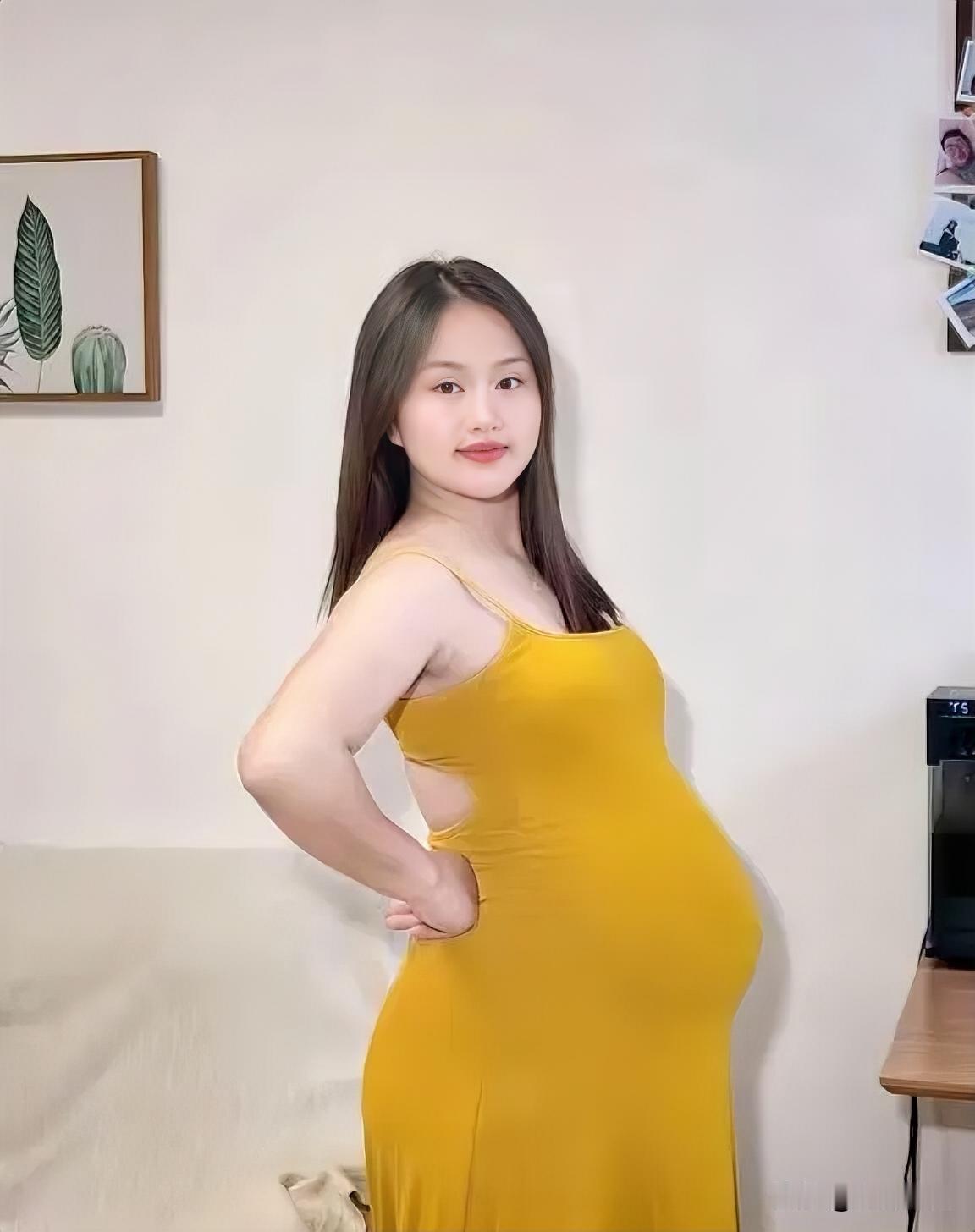这位孕妇穿黄色连衣裙，微笑面对镜头。