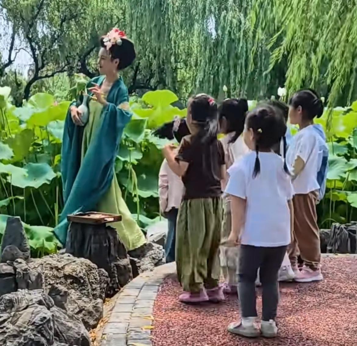 开心又尴尬！6月29日，河南一小姐姐穿着汉服在景区拍照，映着荷花荷叶和柳树的美景
