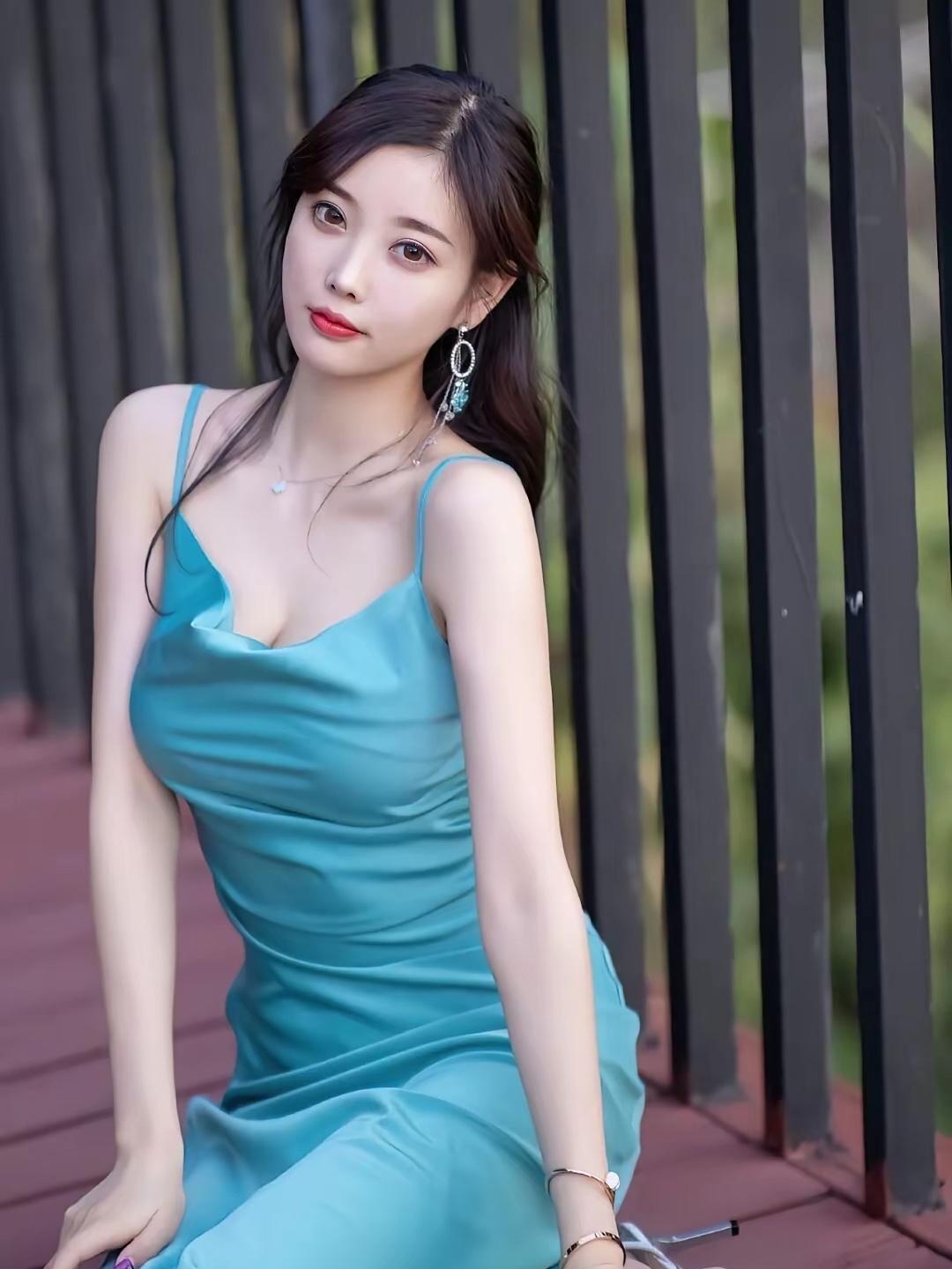 一袭湖蓝色缎面吊带长裙，自带细腻柔光，垂坠的面料勾勒出曼妙身姿。利落的剪裁衬得身
