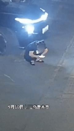 三个奇葩凑在了一起！新疆一女子蹲在汽车前方玩手机，车主从女子面前过去径直开车前行