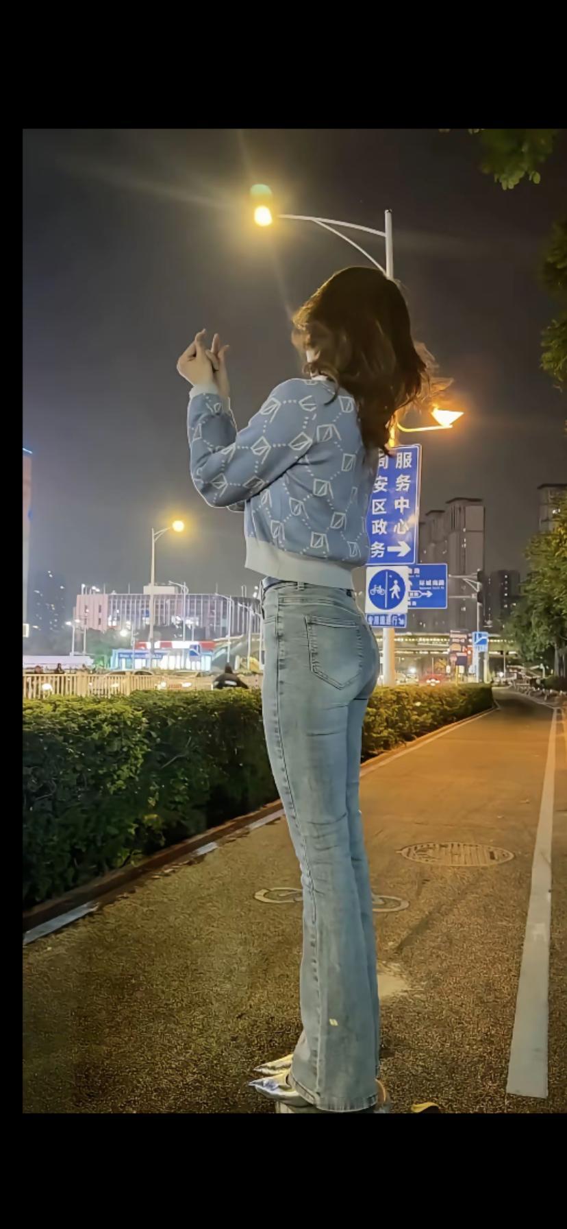 夜晚街头的时尚少女，自信地摆出姿势，享受都市的繁华与自由。