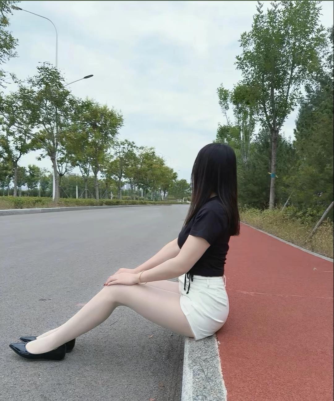 都市女孩的悠闲时光，坐在路边享受宁静。