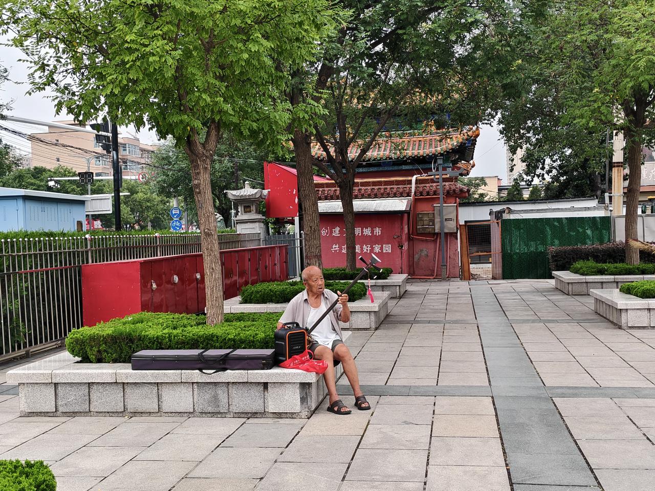 晨起的运城西花园，是充满活力的花园。晨跑时，看到这位大叔坐在花池旁，悠闲自得地弹