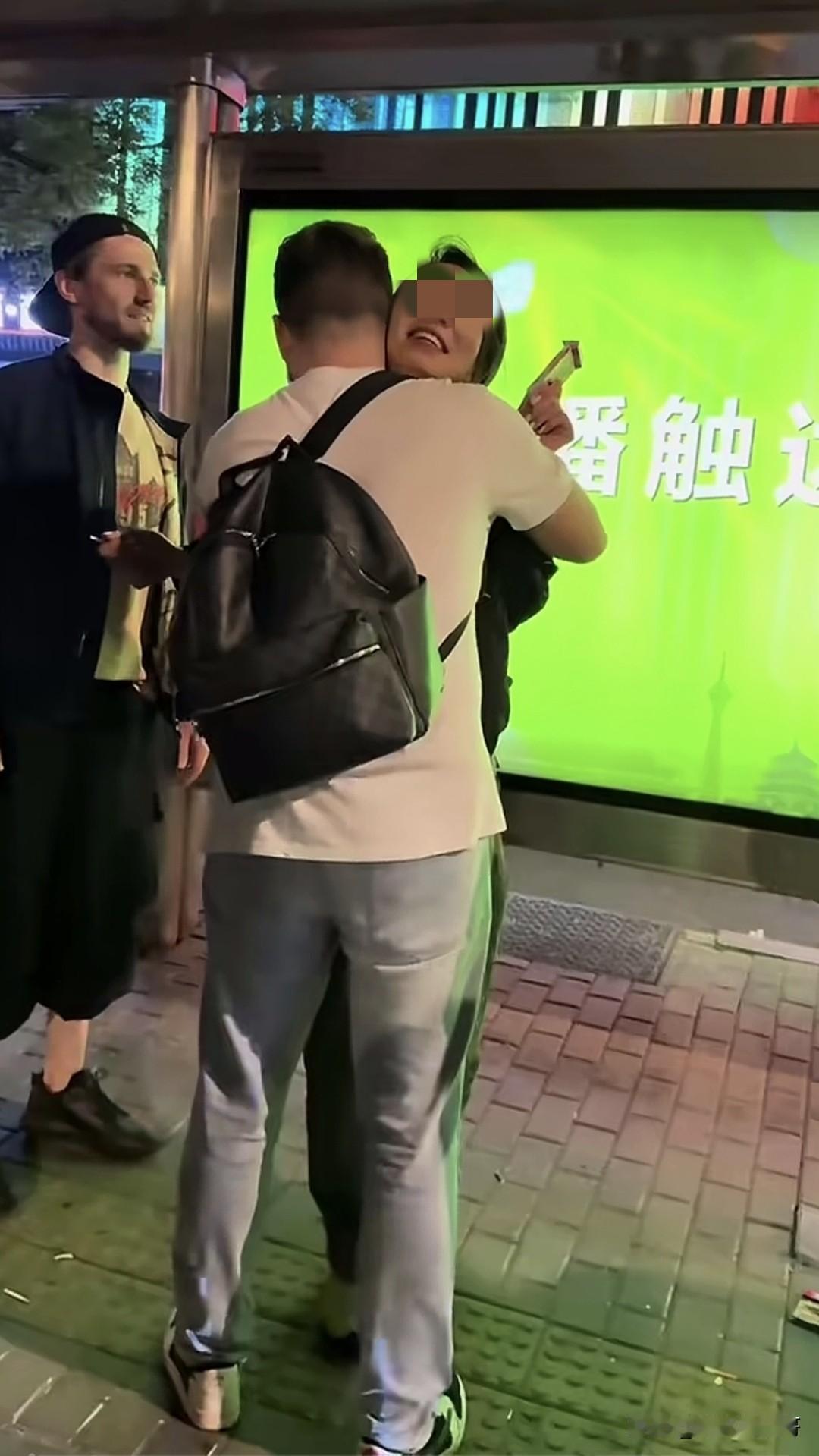 街头一女子分别与两名外国男子热情拥抱，虽然说拥抱是西方常用礼节，但这里是国内啊，