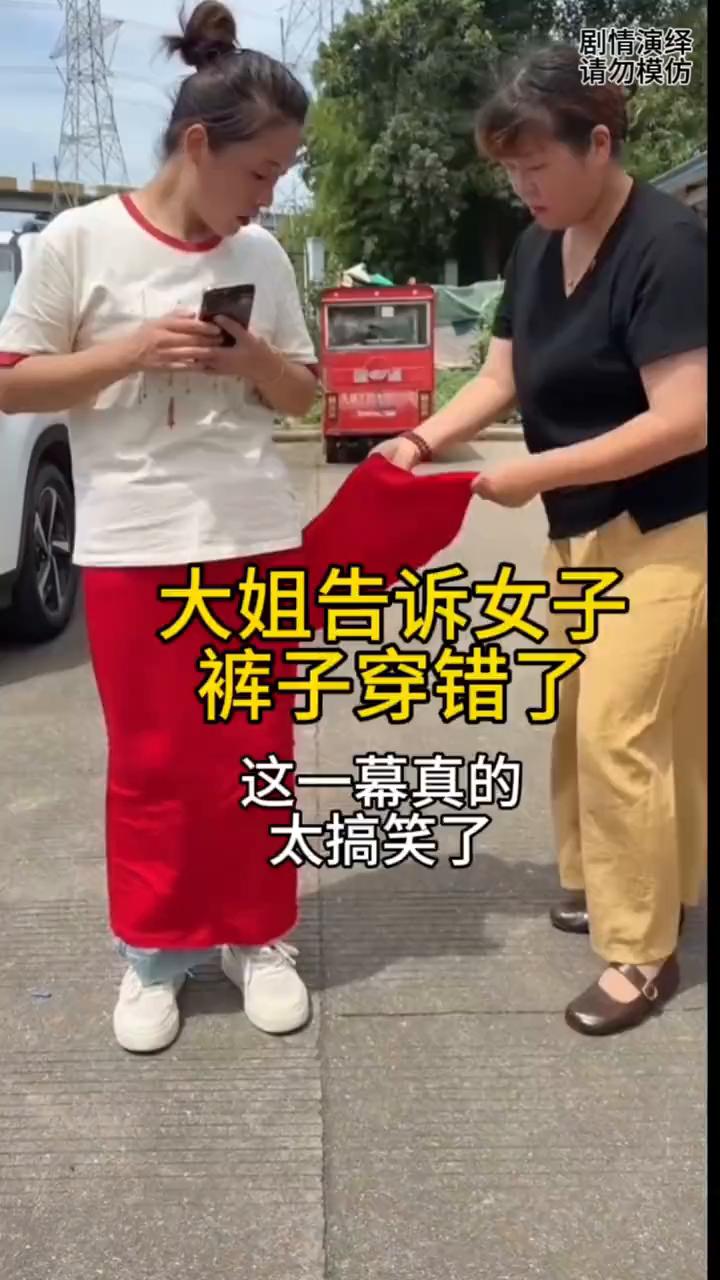 大姐告诉女子裤子穿错了。
女子拿着手机正玩的时候，这时路过大姐叫住了她，然后她告