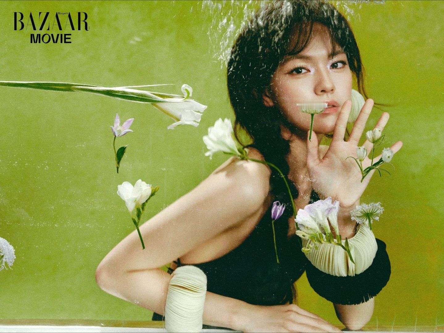 文淇把春天穿在身上了 绿意背景里，文淇身着露背黑裙，与白花相映成趣，清冽的眼神自