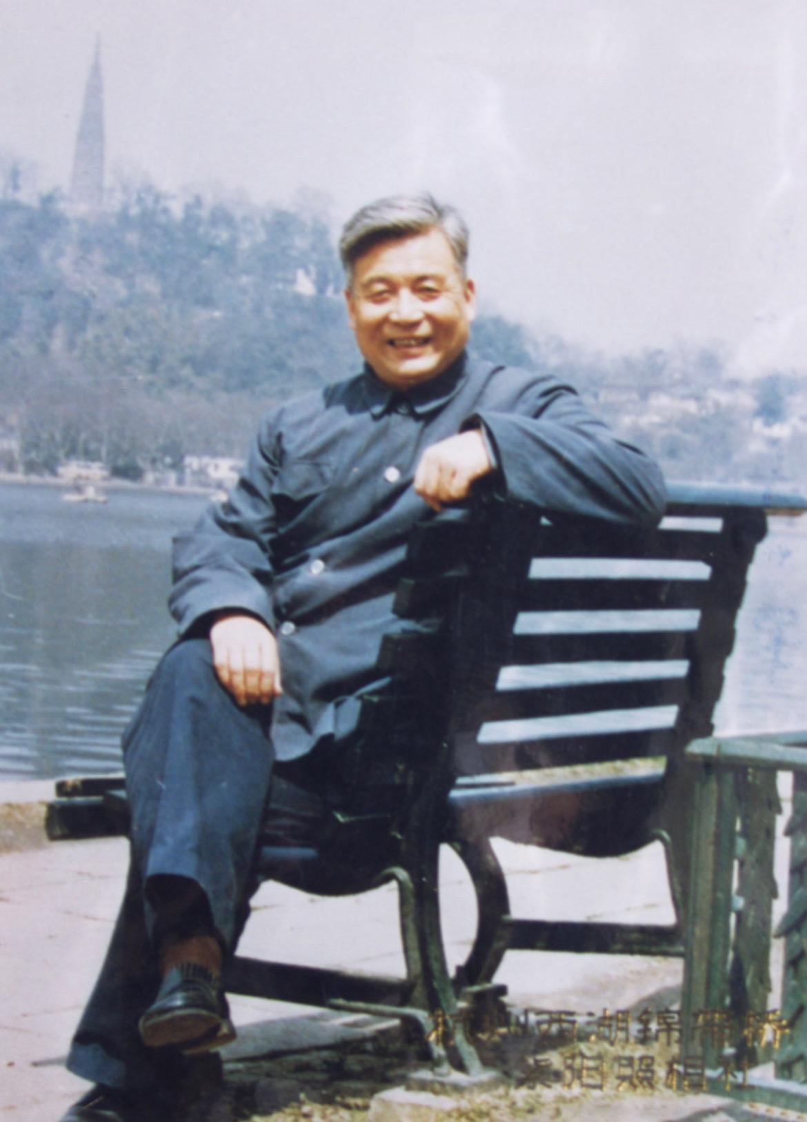 1981年，杭州西湖 邓稼先坐在长椅上，身着中山装皮鞋，背后是湖水，远...