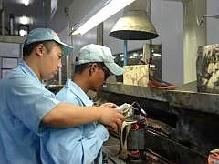 中印两国再次携手：在印度工厂的空调压缩机流水线上，一名中国主管正在指导印度工人作