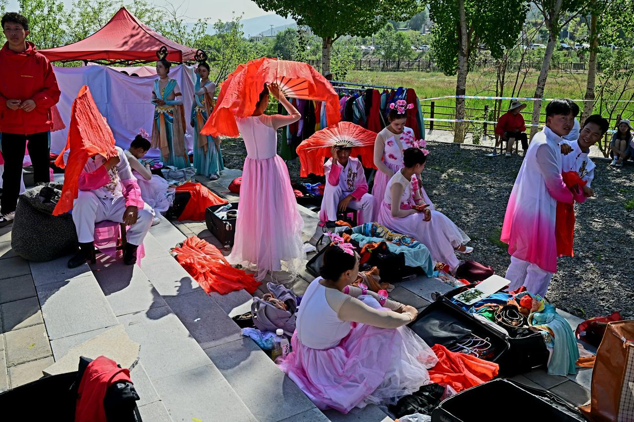 演出开场前，舞台后方的空地上一派忙碌景象。演员们正紧锣密鼓地做着准备，有人对着镜