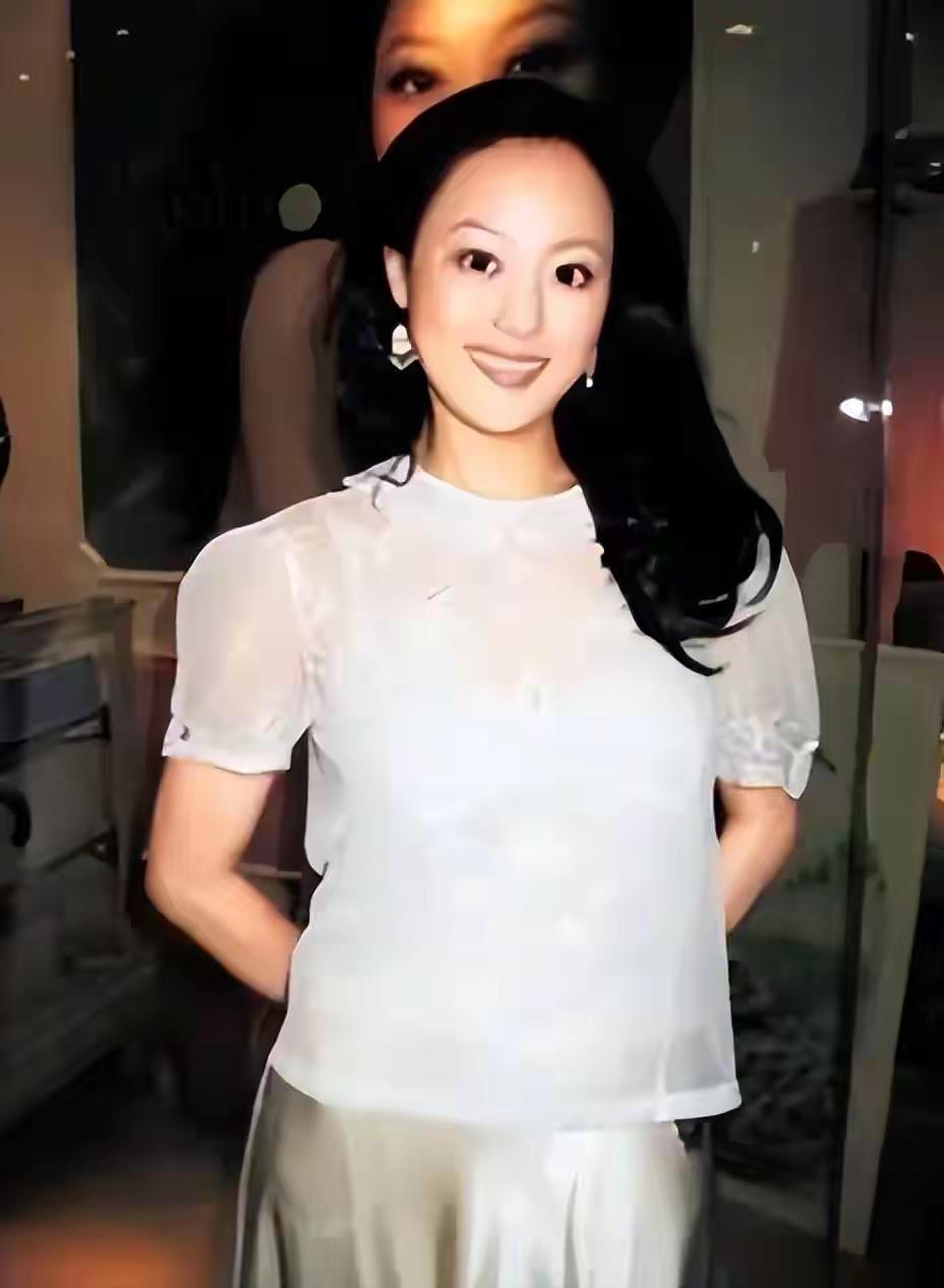 一个穿白衣的女士在微笑。多年不见，还是那么优雅漂亮。还认识这位女士吗？我感觉当年