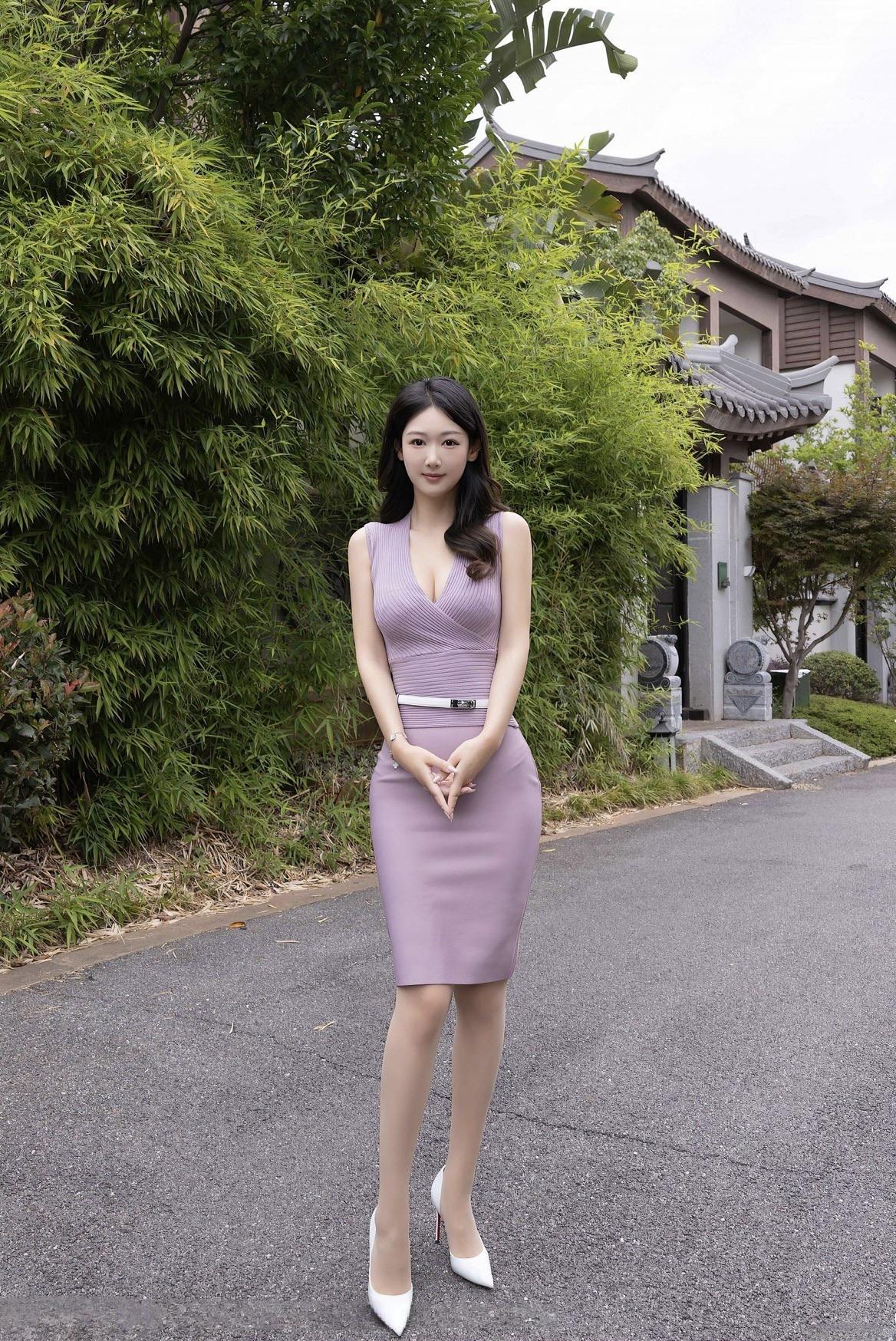 在竹影轻摇的庭院边，她身着淡紫色收腰连衣裙，优雅地立于青石板路上。精致的剪裁勾勒