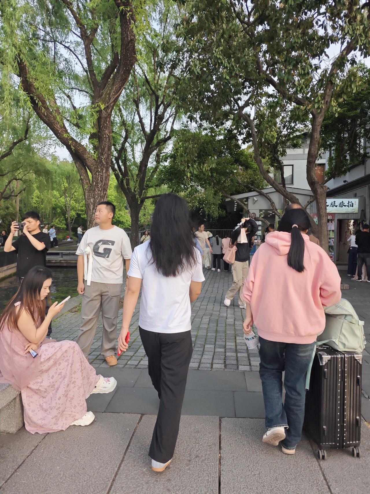 双休日杭州西湖一派热闹景象，猜猜看人潮中有位长发飘飘穿白色T恤黑裤子的背影是男生