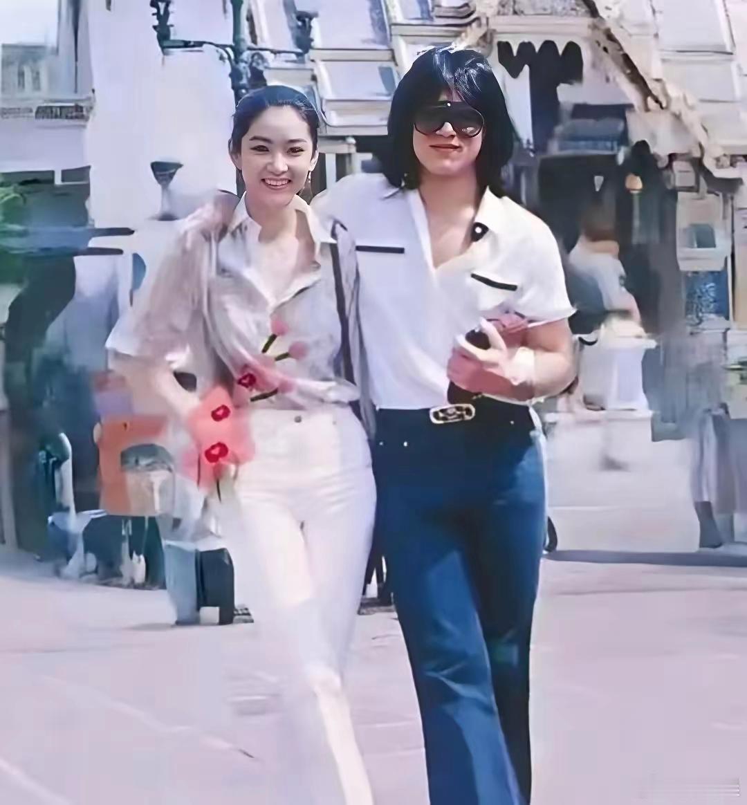 1979年珍贵旧影像，成龙手臂轻揽林青霞，二人并肩漫步在泰国街头。 