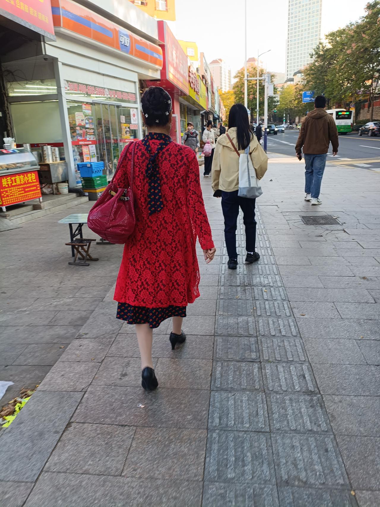 去公交车站，前面一位女士穿着大红色薄款外披，露出一截裙子，肉色袜 下瞪着一双高跟