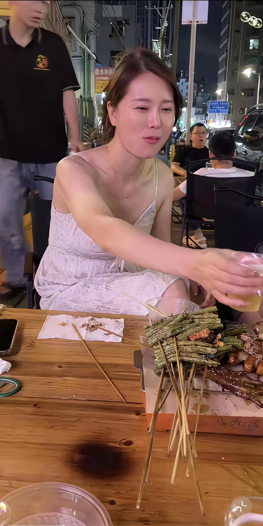 晚风裹着烤串的香气，她举着酒杯，眼里盛着星光。
 
竹签堆起的是生活的热辣，杯里