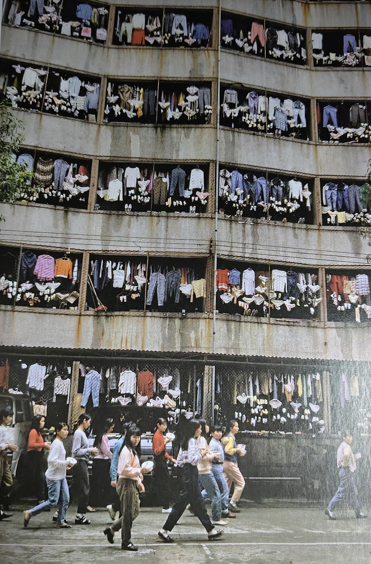 1985年深圳，朱宪民摄影《外来女工的宿舍》。
楼窗挂满晾晒的衣衫，手捧饭盒的打