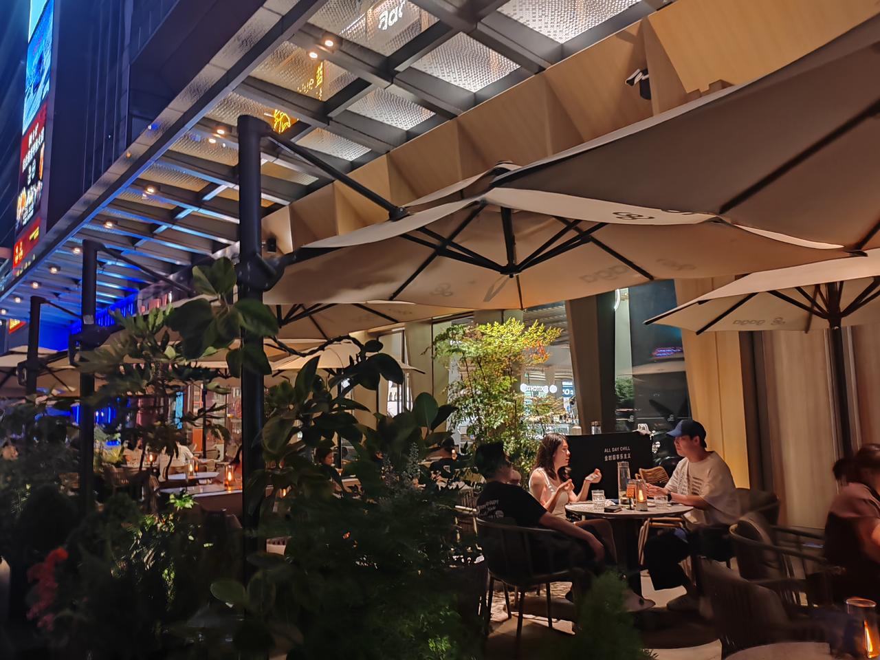 霓虹与暖灯交织，晚风裹着松弛的烟火气。和好友围坐桌前，看城市夜色慢慢沉下来，杯盏