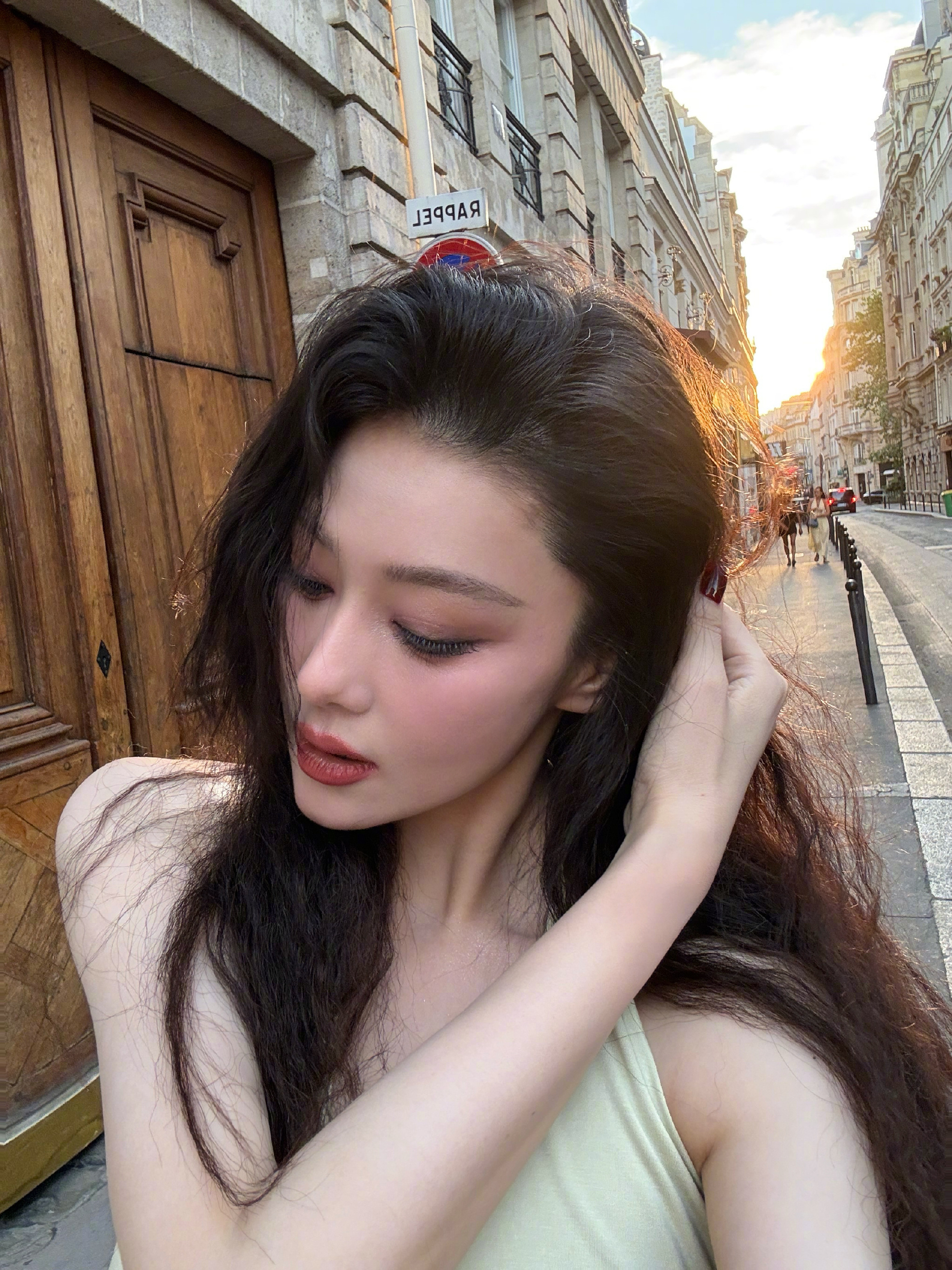 黄昏的落日沿着异国街巷缓缓垂落，暖黄的光线缠上蓬松的长发，像无数细碎温柔的牵绊，