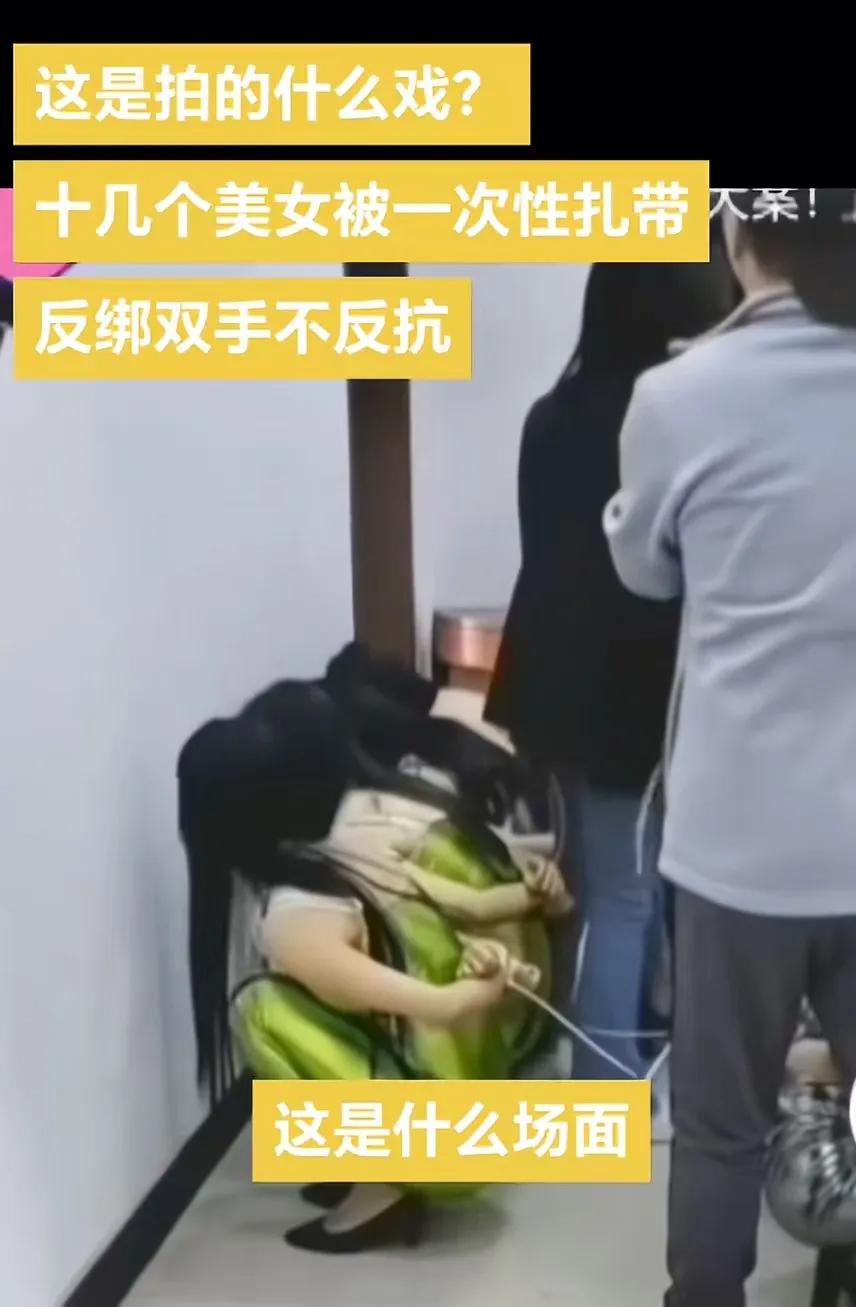 十几个身材火爆的美女被一次性扎带反绑双手，然后被要求蹲在地上，这样的场面引发了热