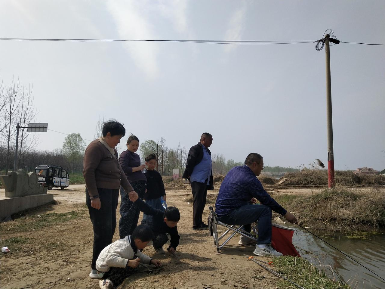 今日老公垂钓，后面围观了一些人。

孩童想让母亲要点鱼喂养！

母亲很客气的说道