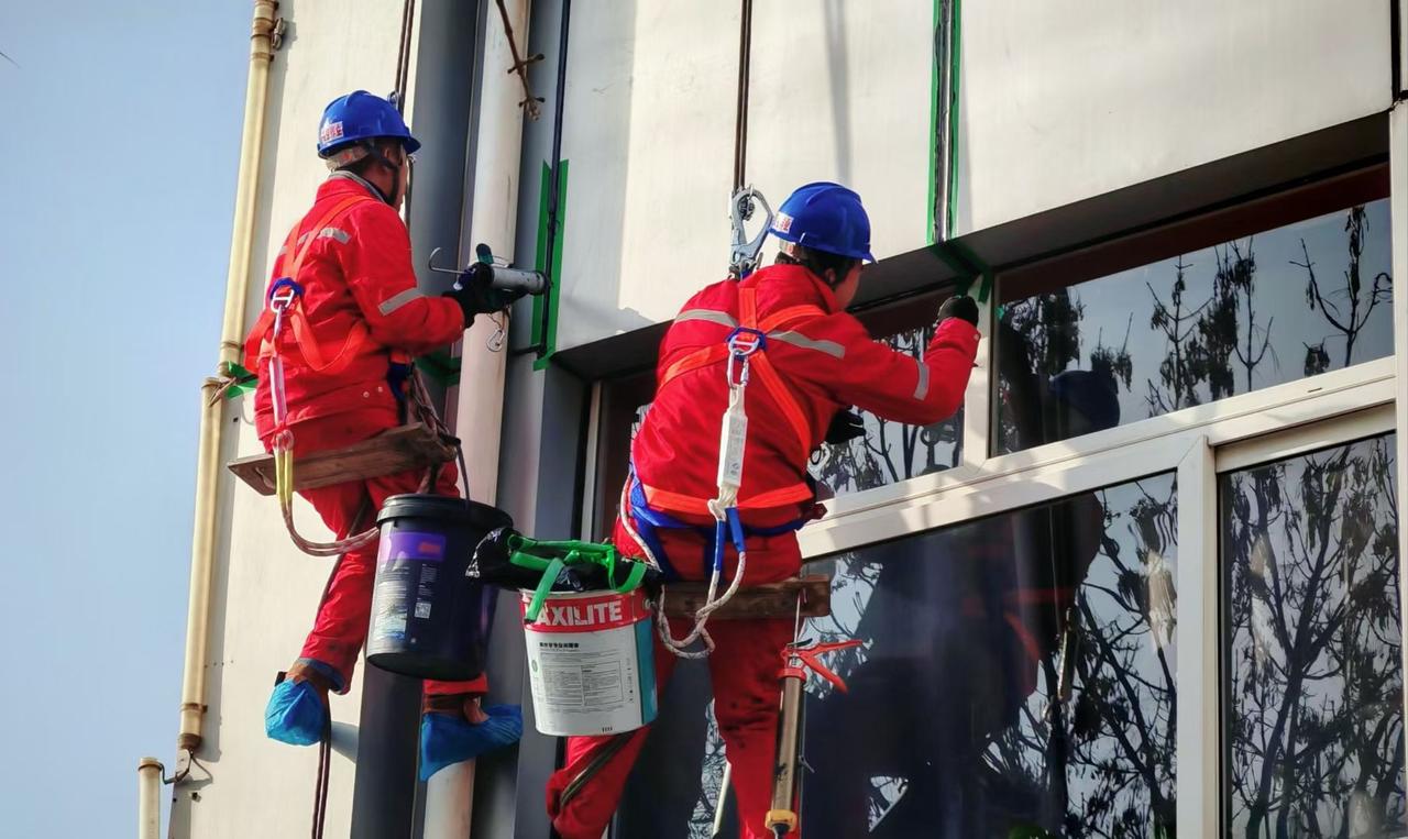 红装悬在楼宇的轮廓里，枯枝筛过的光，落在他稳稳的肩头——高空里的每一步，都是生活