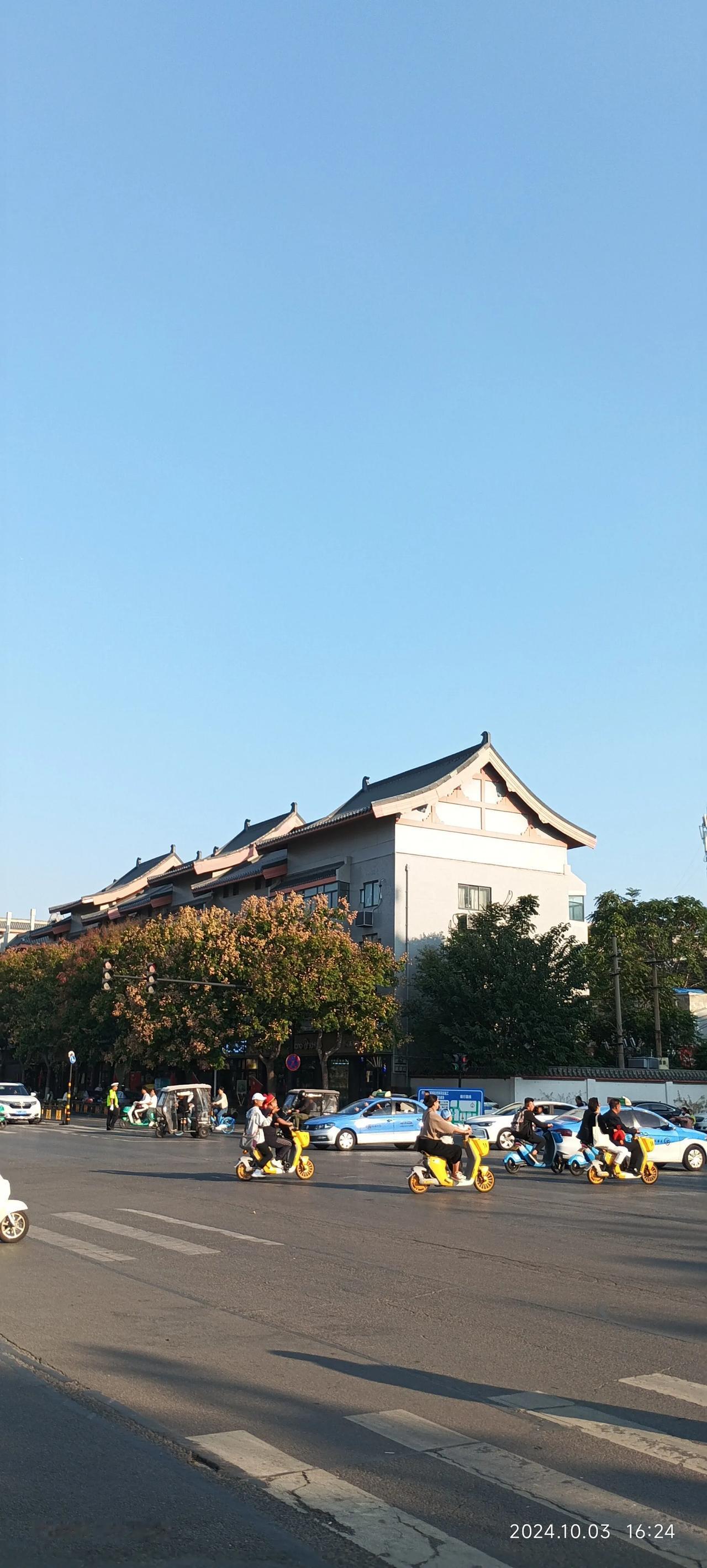 这里是开封市十三中北边的十字路口街景。十三中学的教学大楼古色古香，不同于现在的平