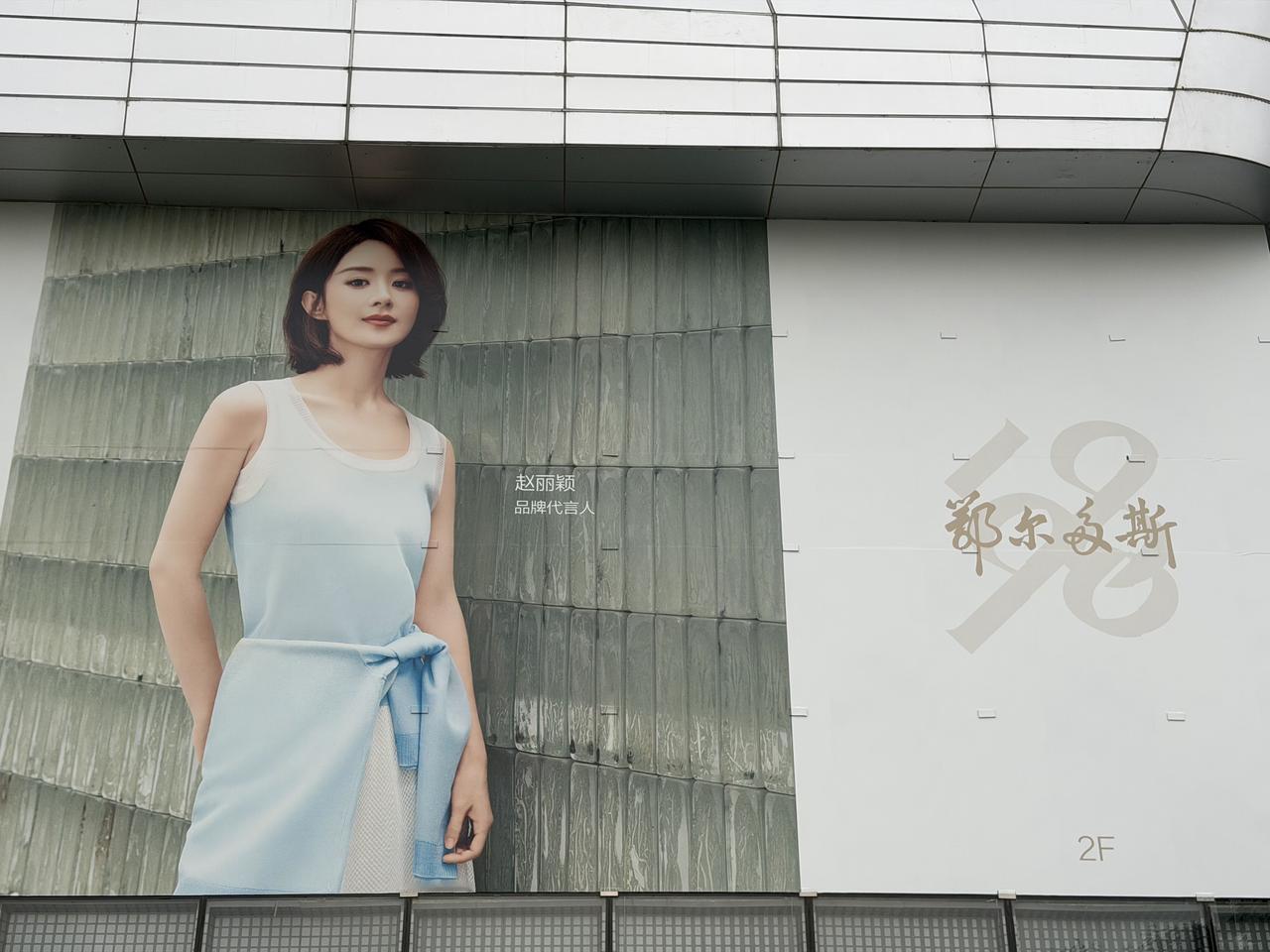 一个穿着裙子的女人站在广告牌前。