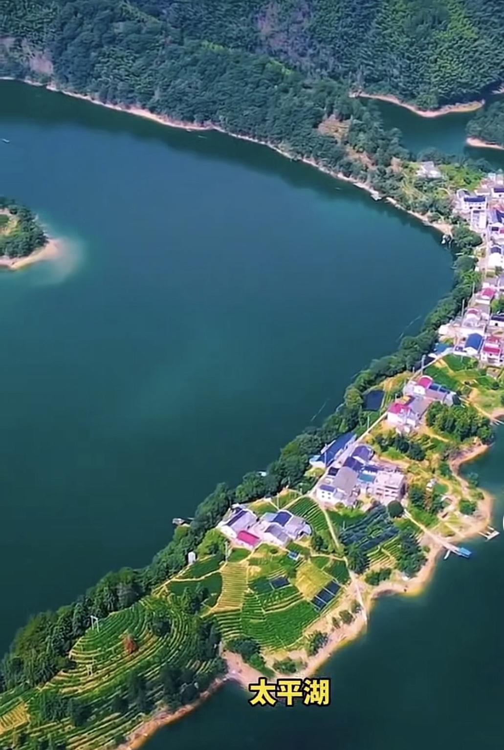 澄澈的深绿色湖面环绕着狭长的半岛型陆地，湖岸线蜿蜒曲折，左侧还露出了一座小型湖心
