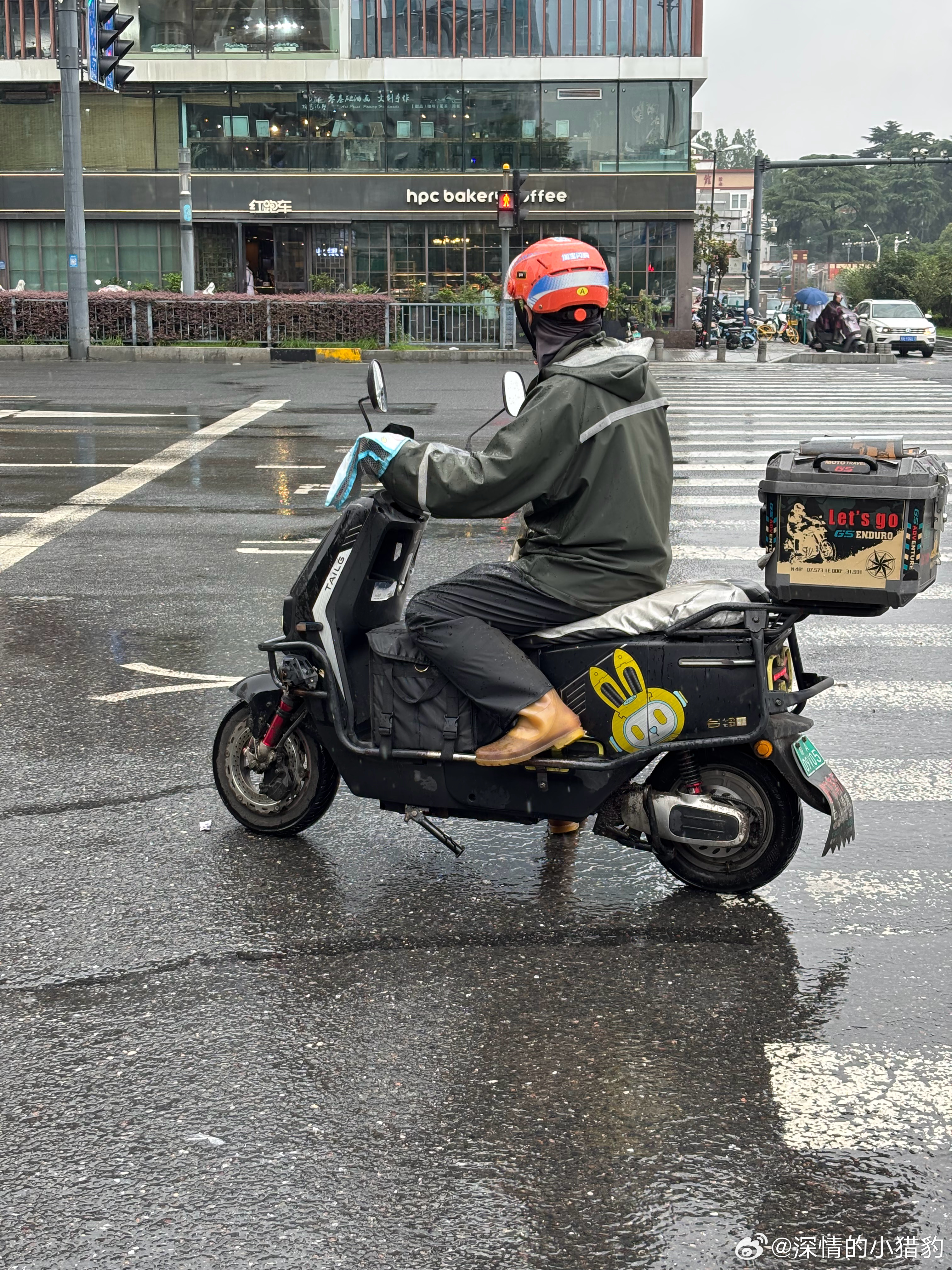 雨衣小哥在路口耐心等待红灯变绿 