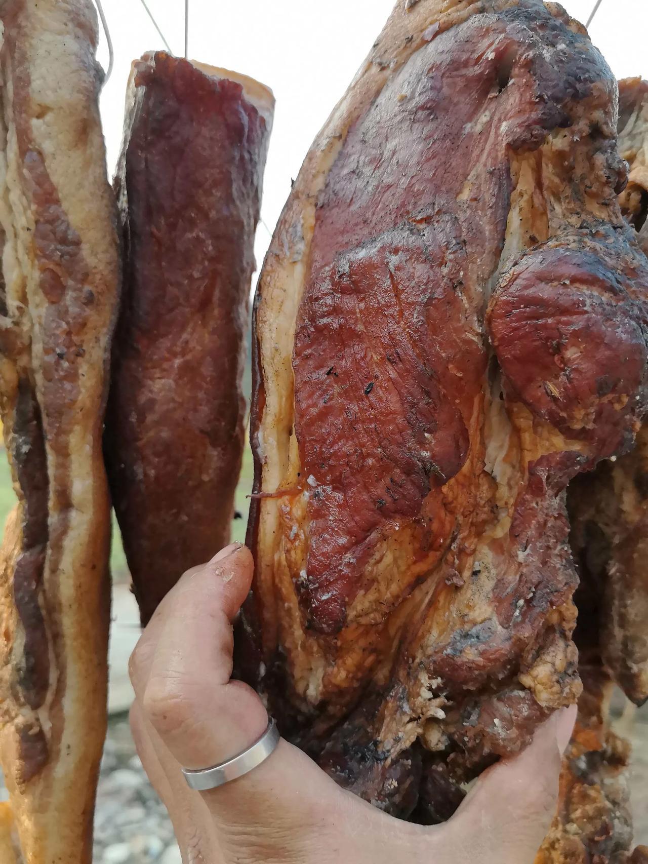 快递盒在玄关蹲成小方碑
拆开时，陈年的烟火
从真空袋里逃出来——

腊肉的皮还泛