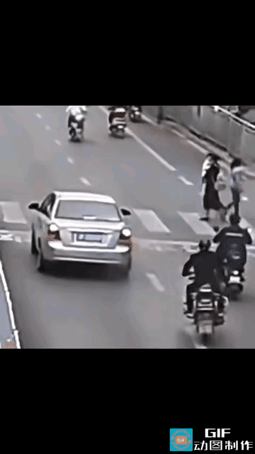 马路上，斑马线上，一个女子正抱着孩子过马路，其他车辆都在斑马线前停下，礼让行人，