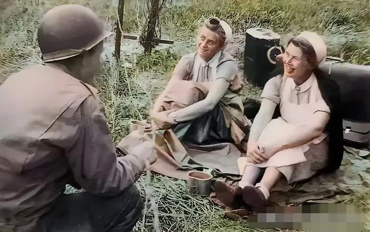 这张照片拍摄于1944年，一名美军在和两名德军女卫生兵俘虏交谈，看他们谈笑风生的