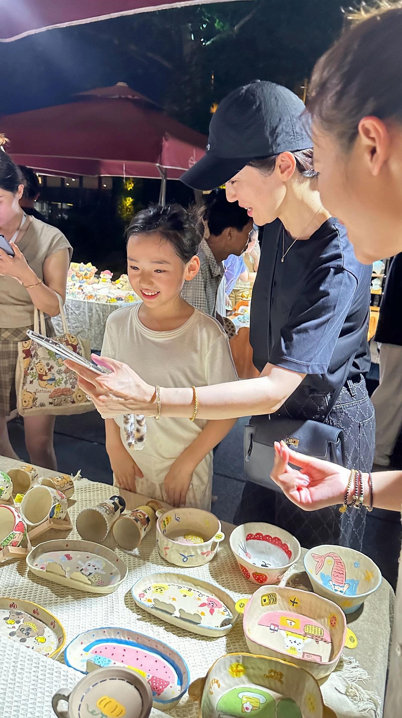 近日，董璇带着女儿现身景德镇市，在陶溪川一摊位旁被偶遇的画面。

小酒窝很喜欢摊