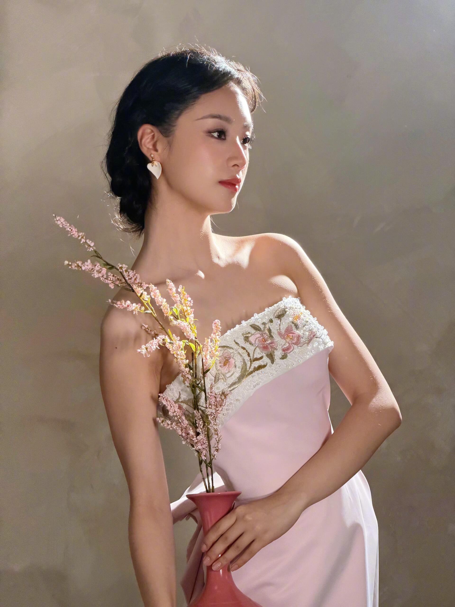 王小亿粉瓷美人王小亿哪里来的古风女子 发髻斜簪玉兰簪，耳坠是青瓷色，裙摆层层叠叠