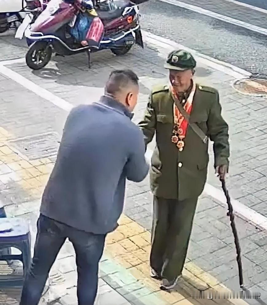 一位老人拄着拐杖从店铺门口经过，坐在门口凳子上的男子自从老人进入视线就目不转睛地