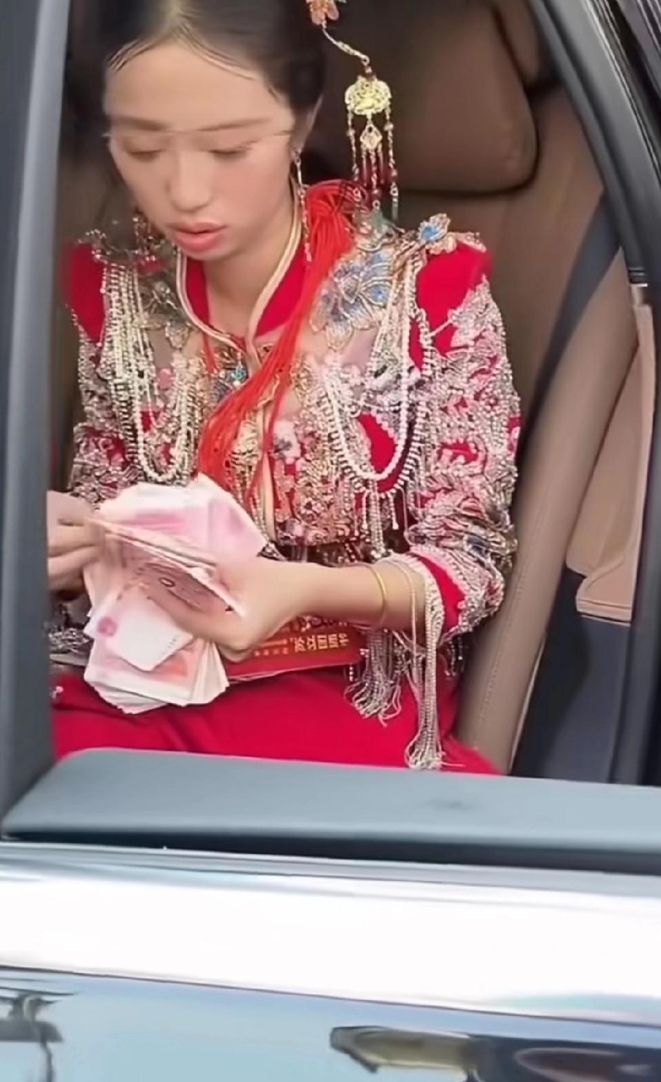 婚礼现场数钱像猪仔交易！
 
新娘穿得珠光宝气，却在婚车里一张一张数钱，这画面咋